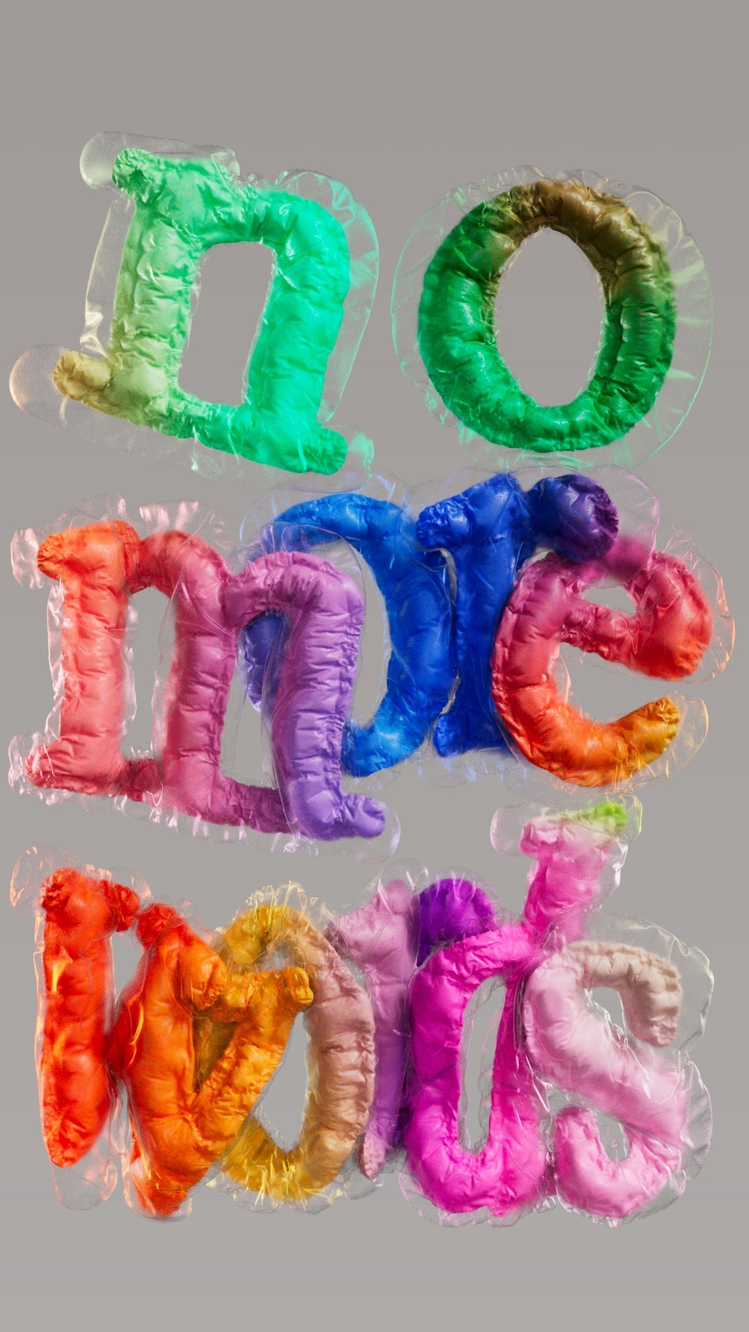 Puffy letters spelling 'no more words' inside clear plastic shells, each letter a different bright color on grey