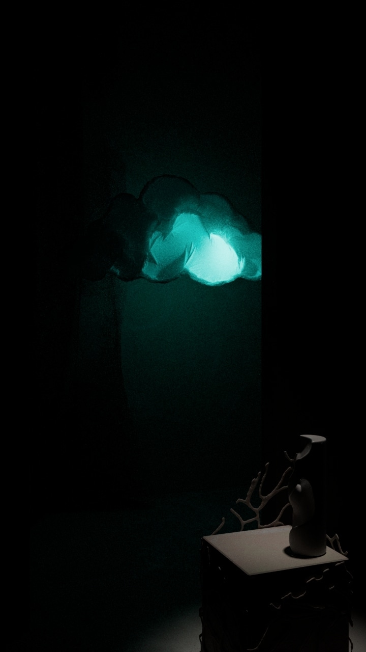 Glowing teal balloon cloud floating in a dark room above a plinth holding a coral branch and a small sculpture